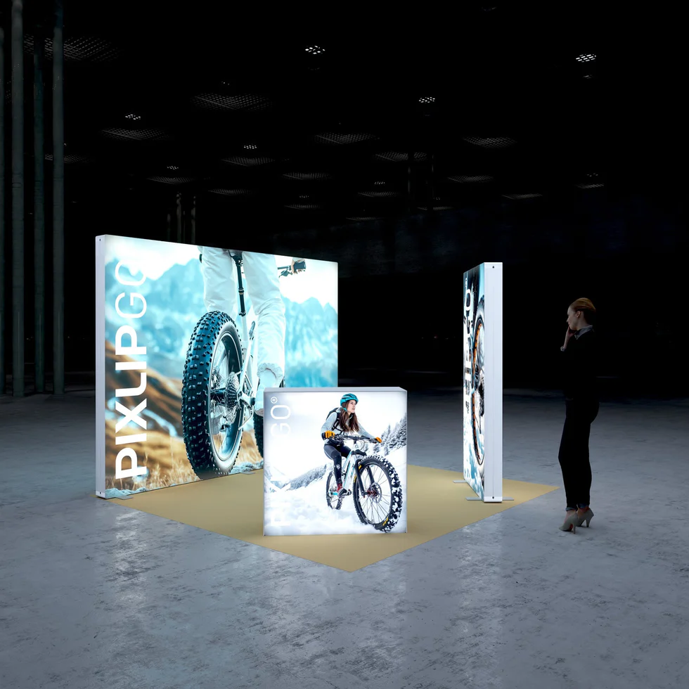 PIXLIP GO Messestand 3x3 m aus linker Perspektive mit großer LED Rückwand, freistehender Stele und beleuchtetem Counter im Fahrrad Design